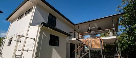 A two-story house with a balcony, a staircase, and a visible outdoor area.