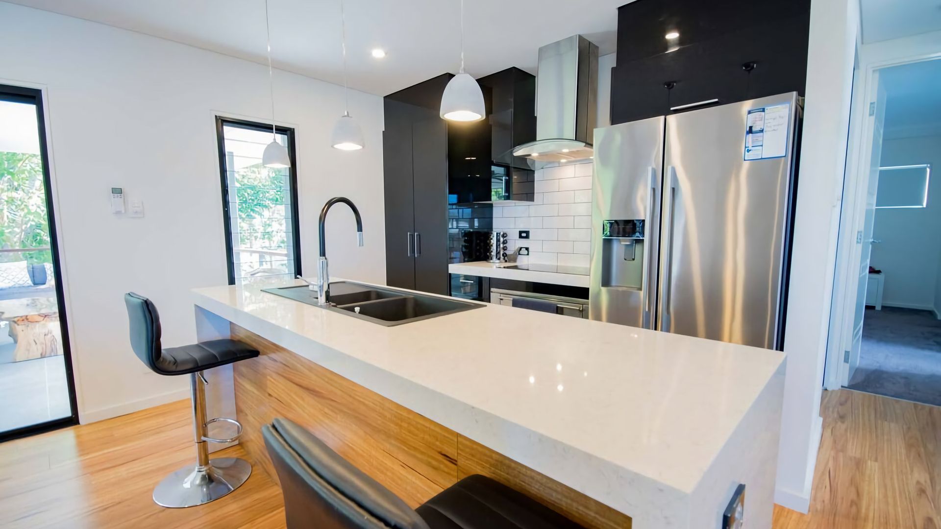A modern kitchen with a large island, stainless steel appliances, and a bar stool.