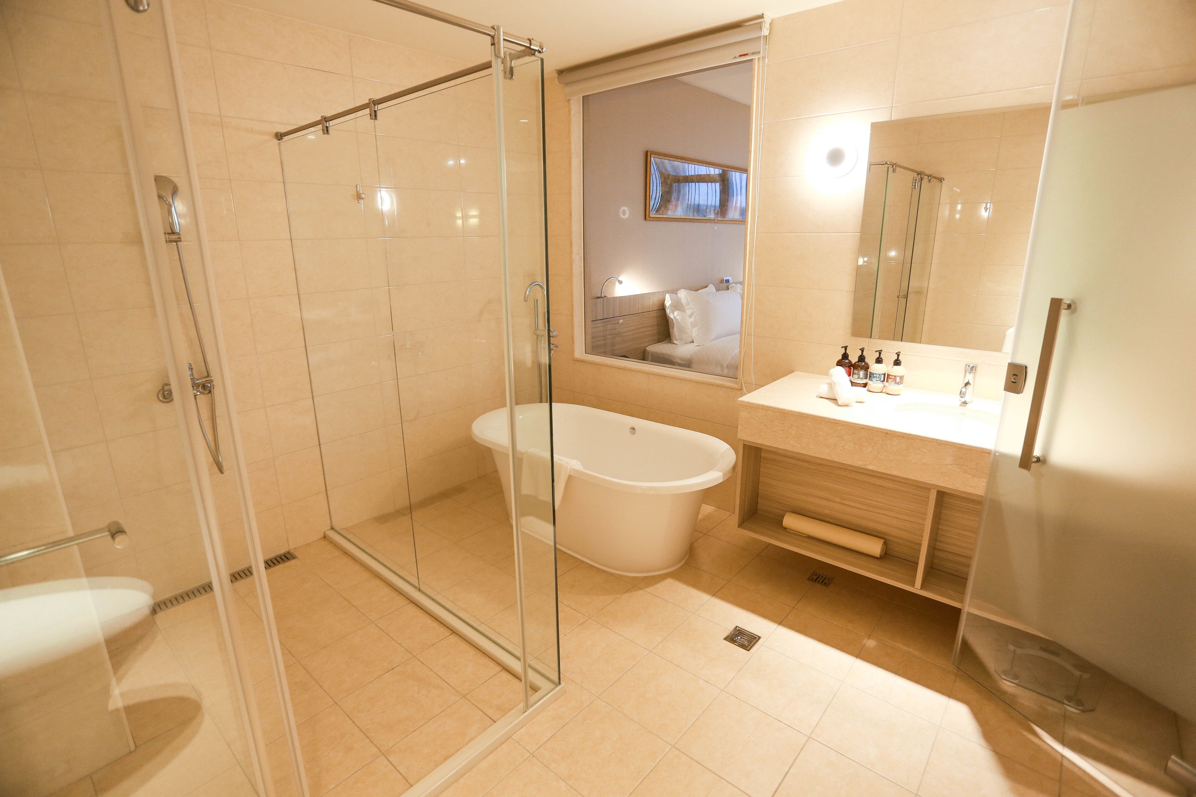 Un baño moderno con ducha envuelta en vidrio, bañera independiente y tocador con espejo.