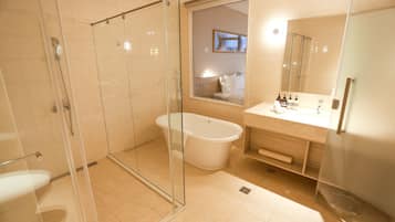 Un baño moderno con ducha envuelta en vidrio, bañera independiente y tocador con espejo.