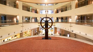 A multi-level atrium with a central circular floor design, glass railings, and a ship's wheel sculpture. - AJ Hotel Hsinchu (Zhubei)