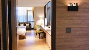 A hotel room with a bed, a chair, a desk, and a large window. - AJ Hotel Hsinchu (Zhubei)