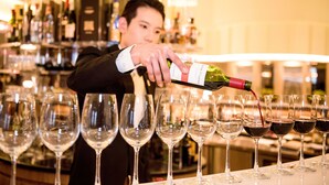 A bartender pouring wine into glasses at a bar. - AJ Hotel Hsinchu (Zhubei)