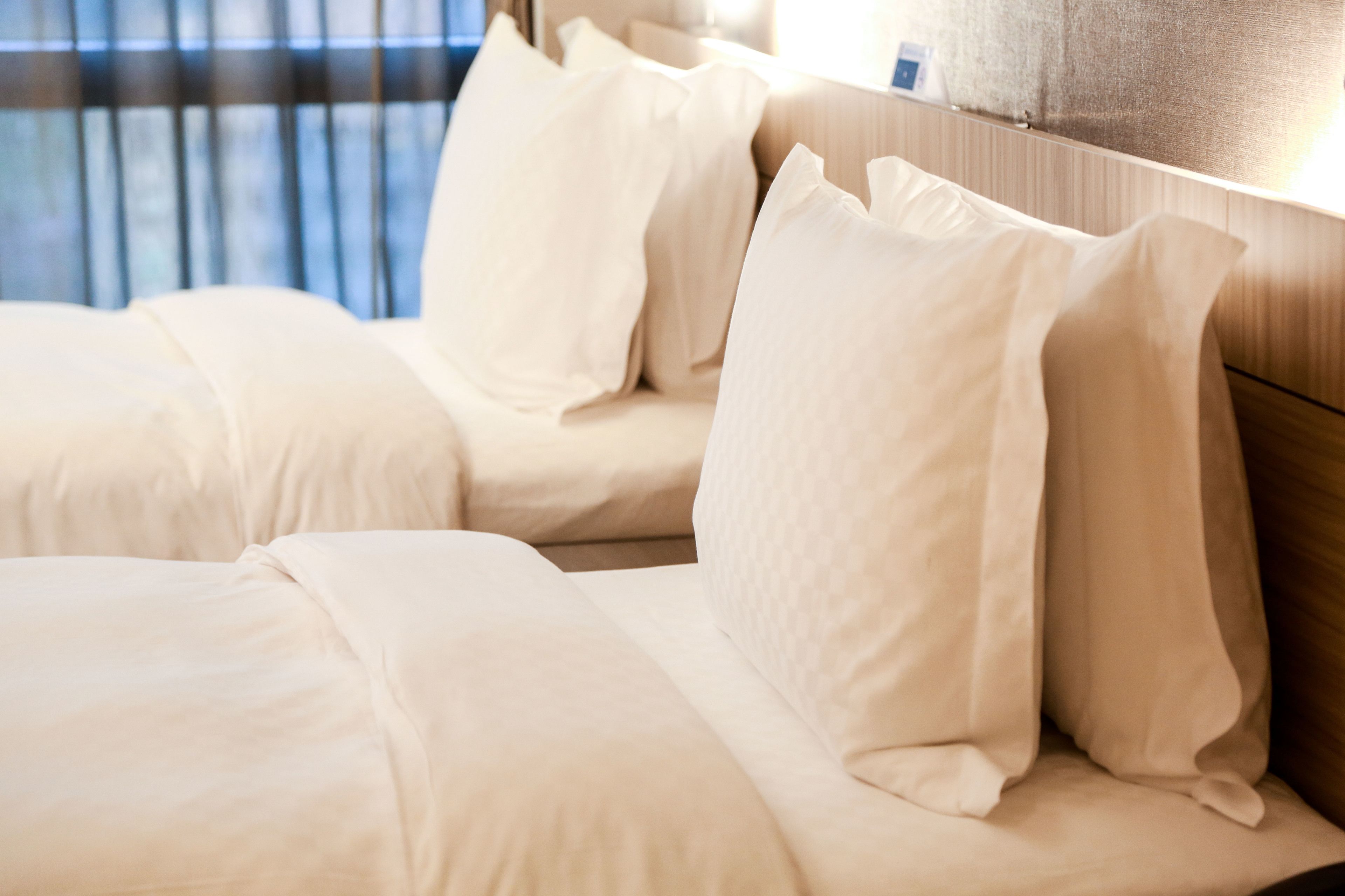 A hotel room with a bed featuring white bedding and a wooden headboard.
