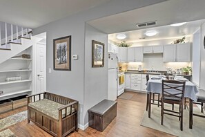 A modern kitchen with white cabinets, a dining table, and a bench.