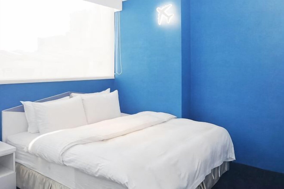 Een hotelkamer met een bed, nachtkastje en raam.
