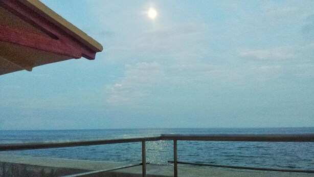 A view of the ocean from a balcony with a metal railing and a red awning. - Luzmin BH - Beachfront Cottages (Oslob)