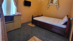 A bedroom with a bed, a wardrobe, a television, and a window with curtains. - Luzmin BH - Beachfront Cottages (Oslob)