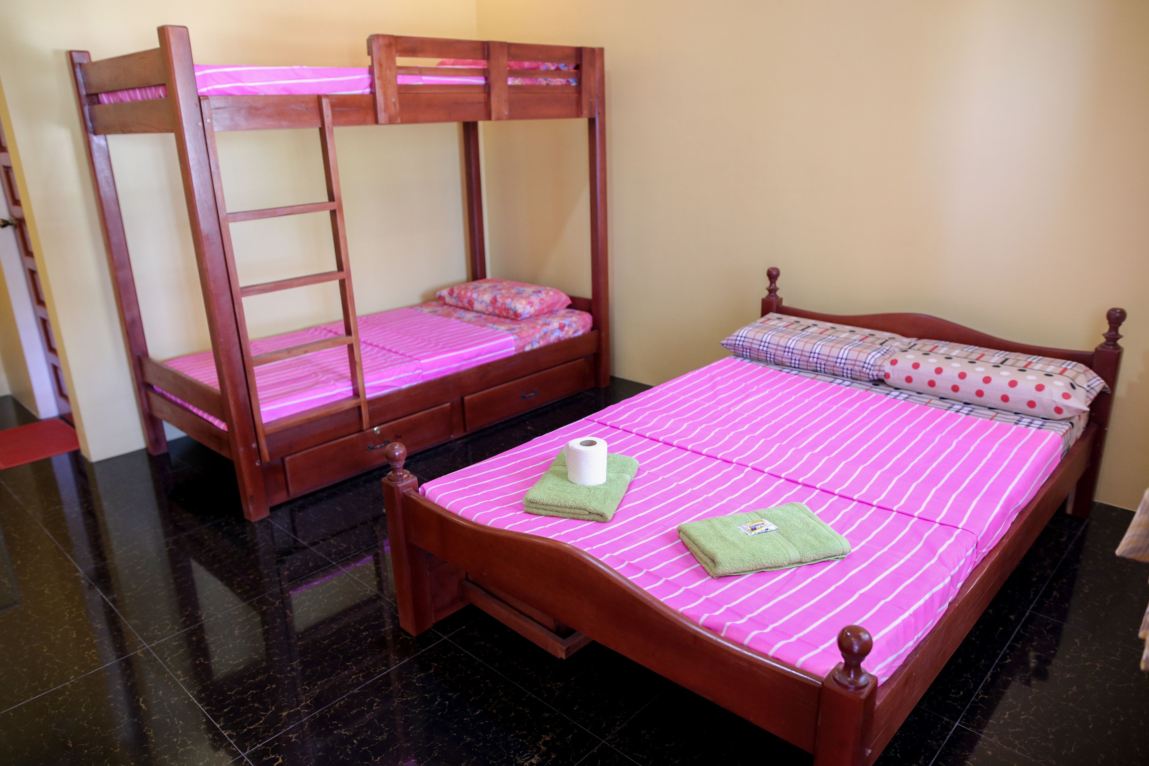 A room with two wooden bunk beds, one with a ladder and one without.