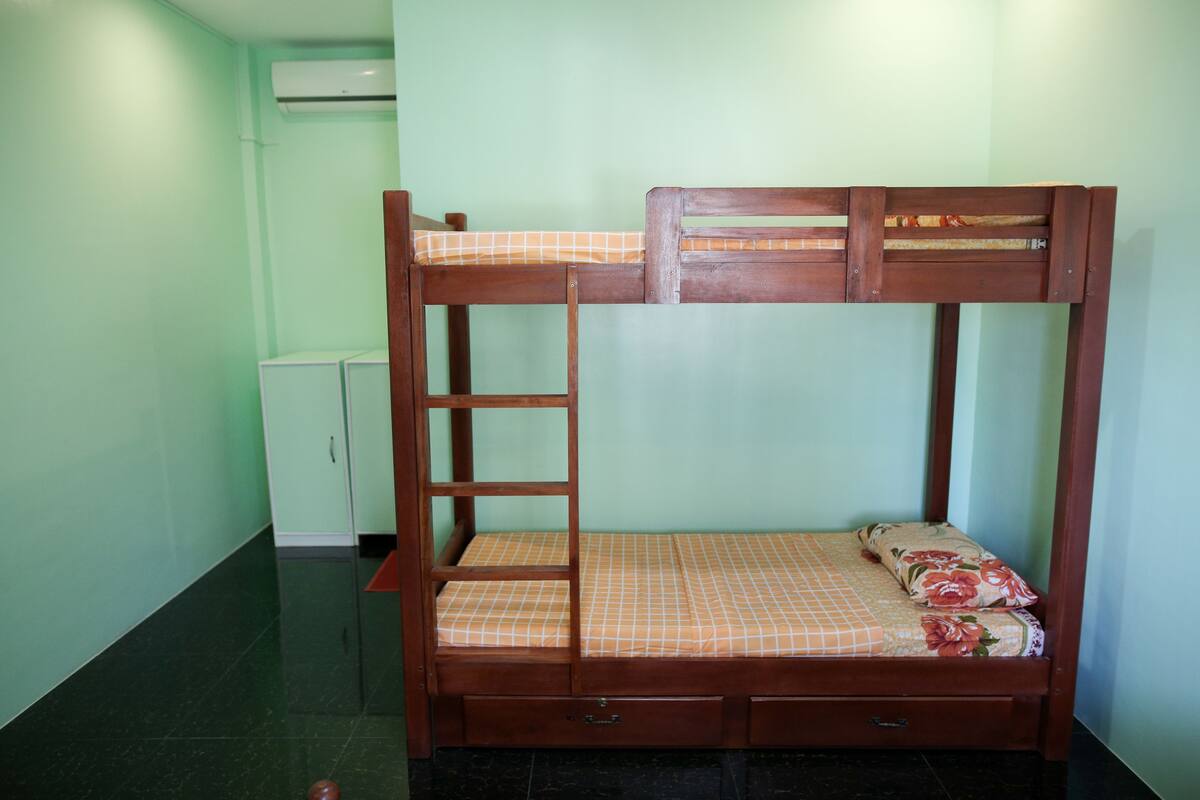 A bunk bed with a ladder, a small cabinet, and a tiled floor.