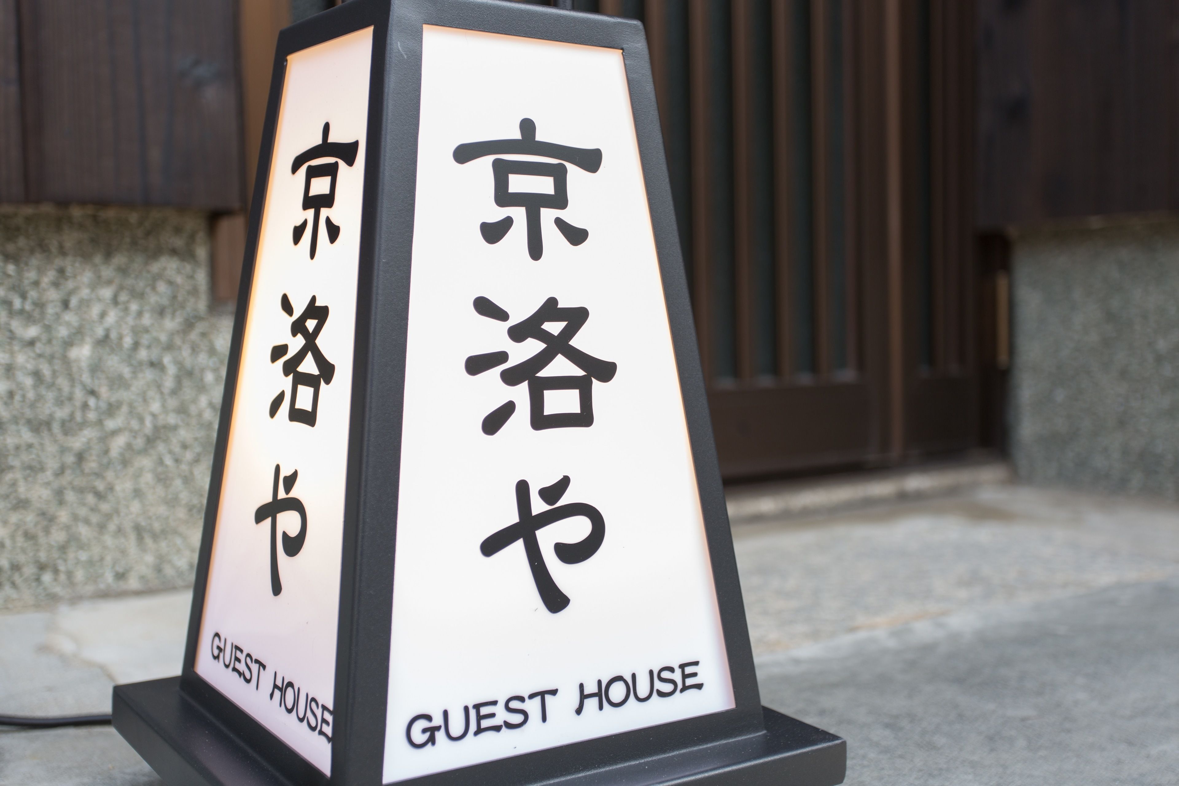 A sign for a guest house with Japanese characters and the English text "GUEST HOUSE".