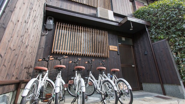 A building with a wooden facade, a set of bicycles parked in front, and a sign above the entrance. - Guest House Kyorakuya Kinkakuji (Kyoto)