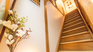 A wooden staircase with a vase of white flowers on the left. - Guest House Kyorakuya Kinkakuji (Kyoto)