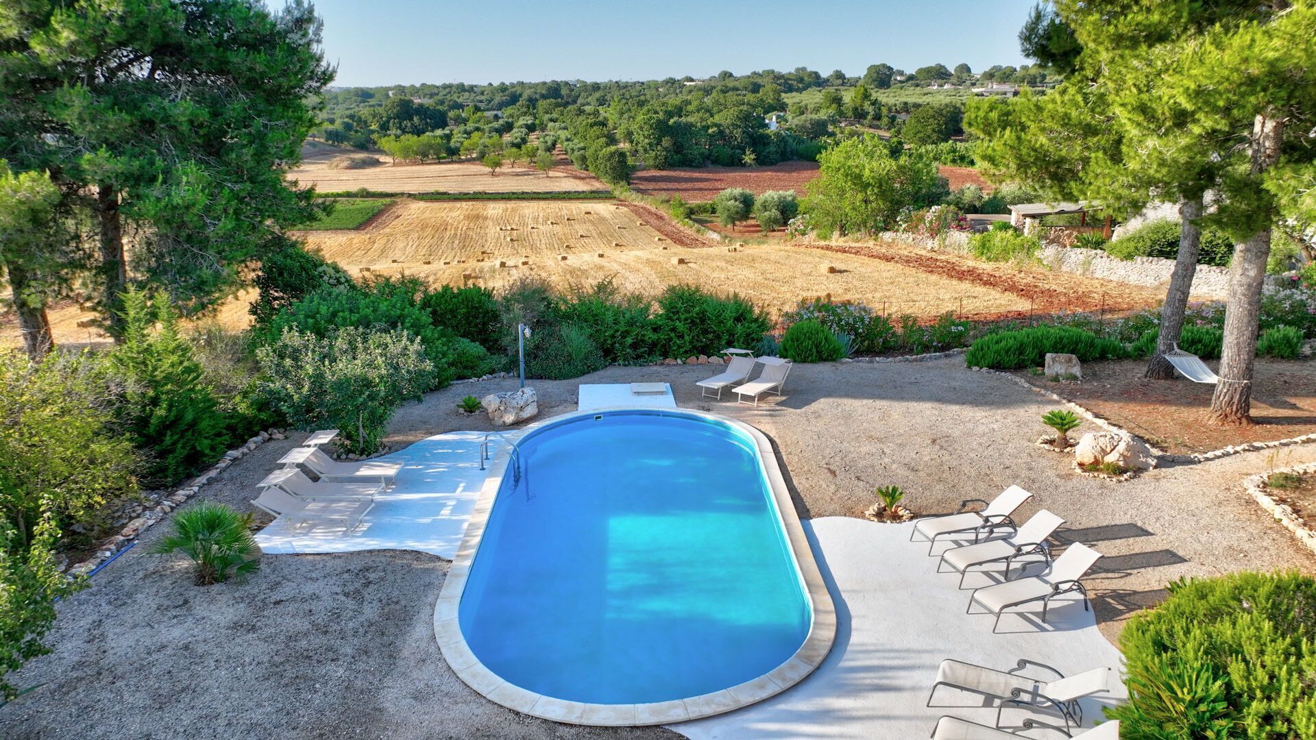 A swimming pool with lounge chairs and a view of the surrounding landscape.