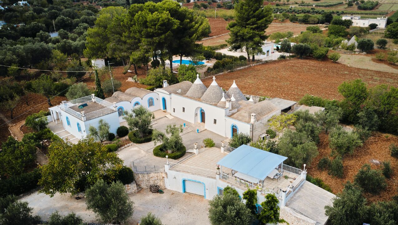 A white building with blue accents, surrounded by trees and fields.