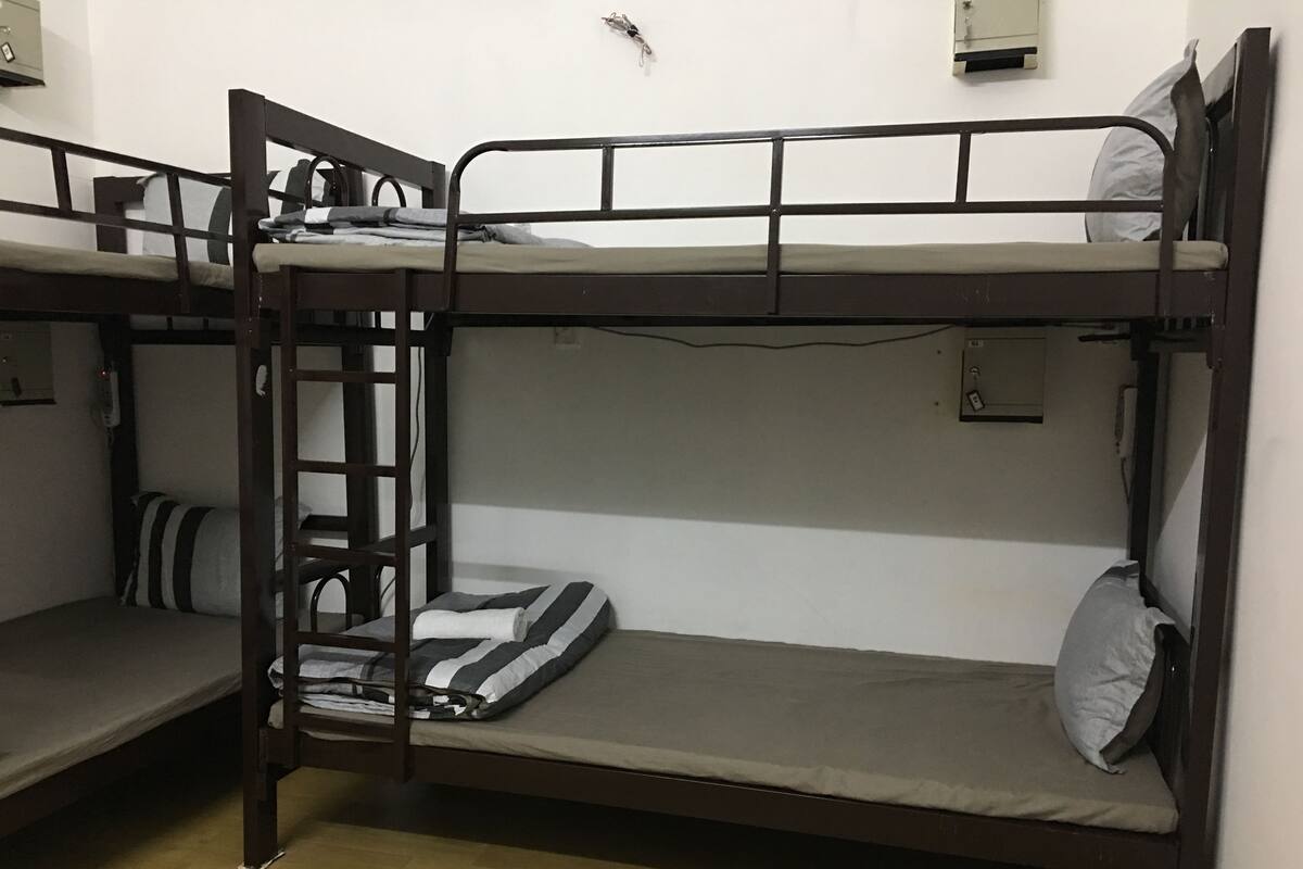 Une chambre avec un lit superposé, une échelle, un bureau et une chaise.
