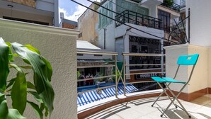 Un balcon doté d’un sol à rayures bleues et blanches, d’une chaise verte et d’une plante.