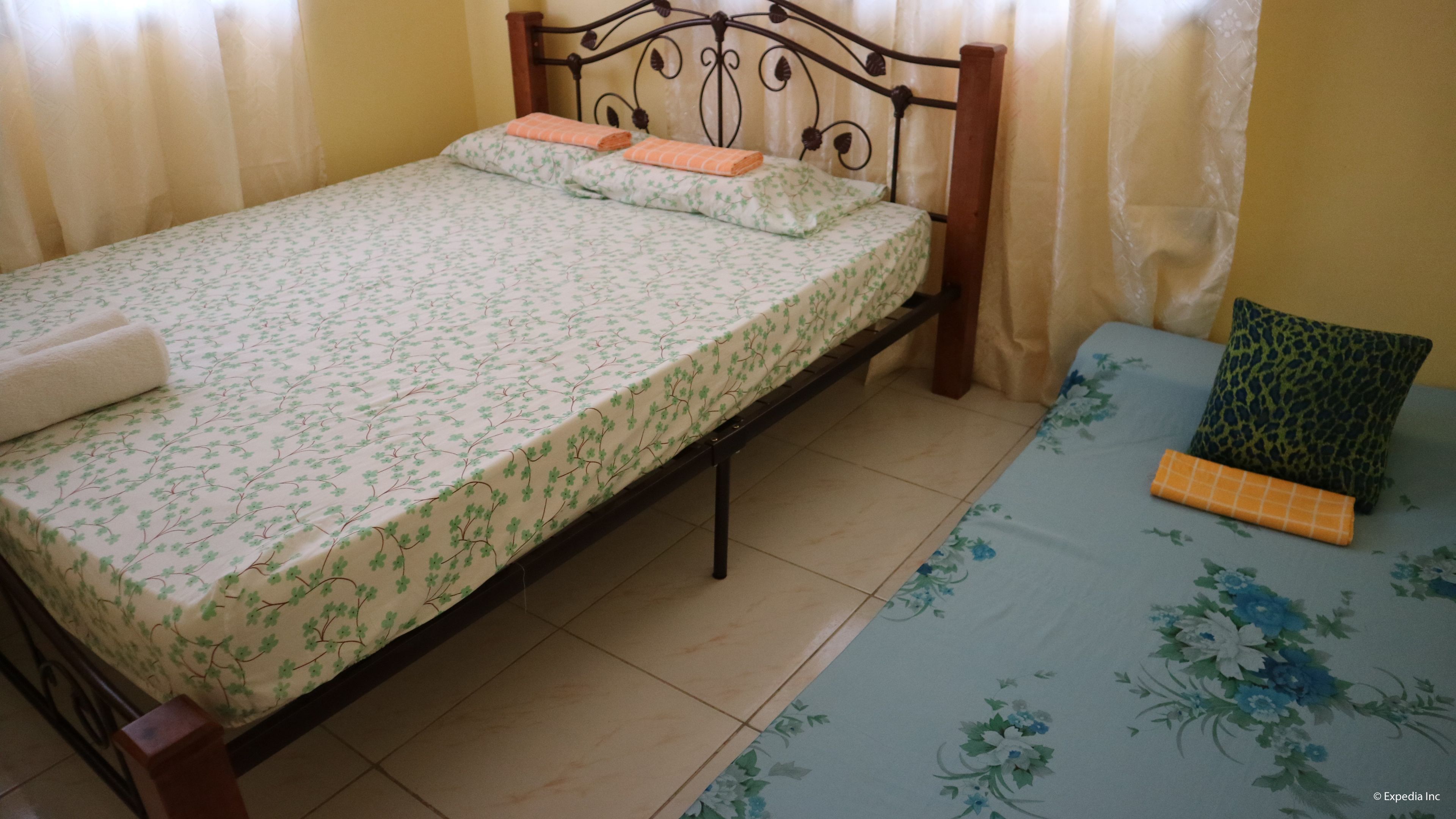 A single bed with a floral bedspread, a wooden headboard, and a small bedside table with a pillow.