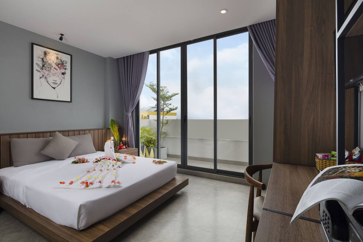 Una habitación de hotel moderna con una cama, un escritorio y un ventanal grande.