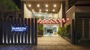 A hotel entrance with a sign reading "MARILYN HOTEL AND RESTAURANT," a gated driveway, and a pathway leading to the entrance. - Marilyn Nha Trang Hotel (Bac Nha Trang)