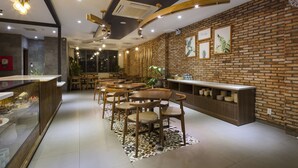 A modern restaurant interior with brick walls, wooden tables and chairs, and a counter with a display of dishes. - Marilyn Nha Trang Hotel (Bac Nha Trang)