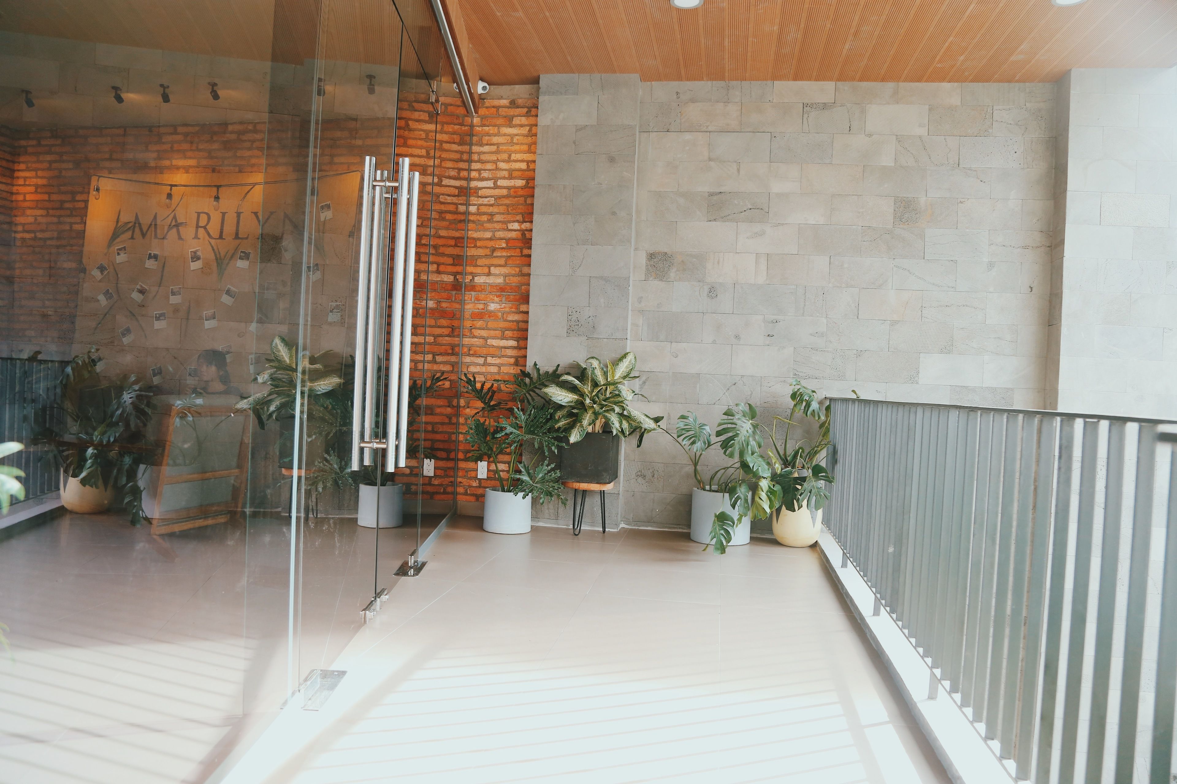 A modern interior with a glass partition, a brick wall, and potted plants.