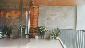 A modern interior with a glass partition, a brick wall, and potted plants. - Marilyn Nha Trang Hotel (Bac Nha Trang)