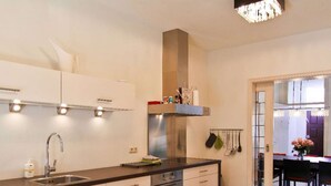 A modern kitchen with a central island, stainless steel appliances, and a hanging pot rack.