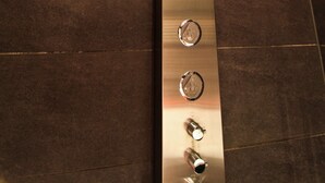 A modern bathroom with a curved showerhead and control knobs.