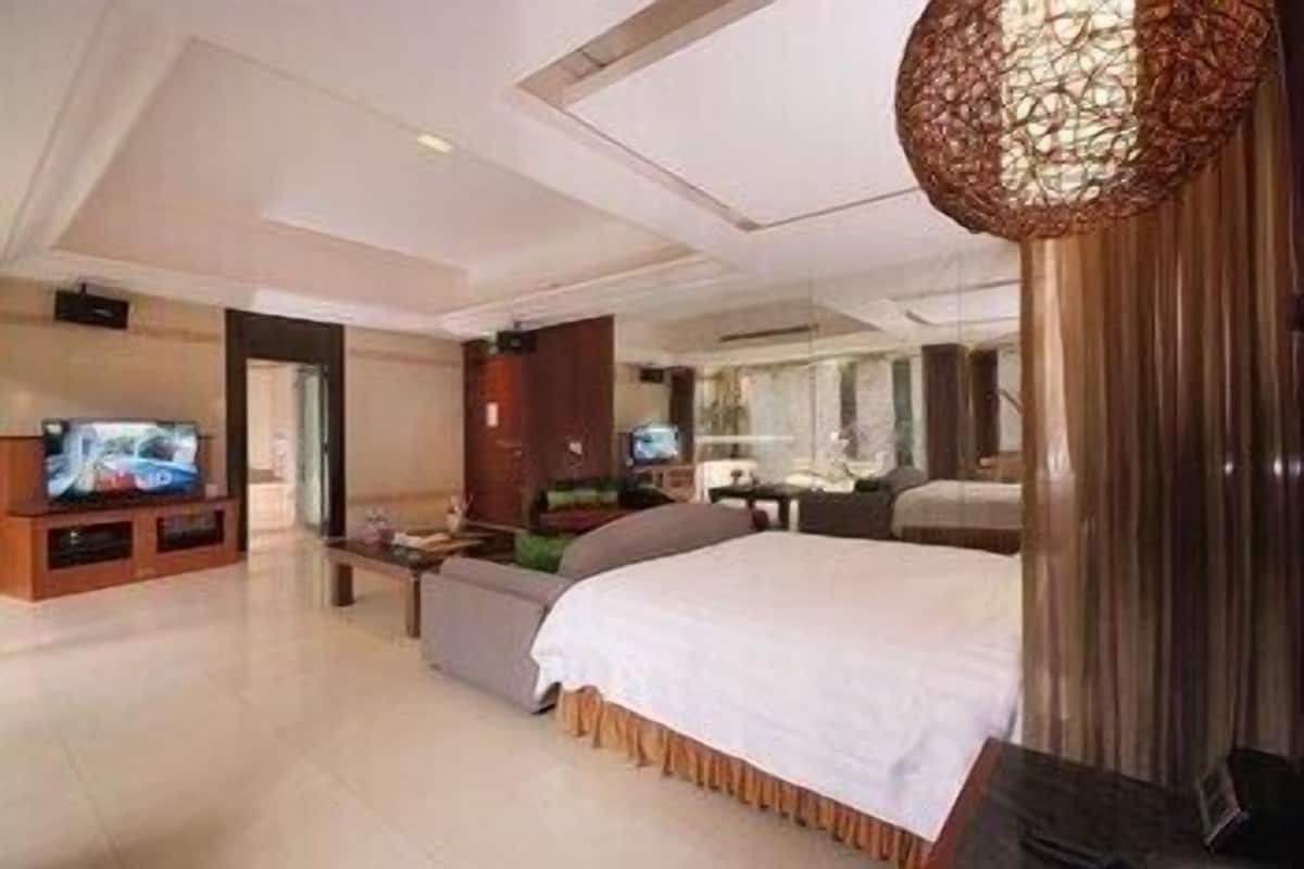 A modern hotel room with a large bed, a television, a desk, and a bathroom.