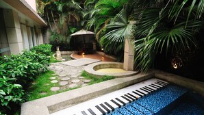 A pool area with a tiled deck, palm trees, and a stone pathway. - Q Motel (New Taipei City)