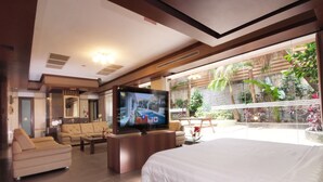 A spacious hotel room with a large bed, a sofa, a television, and a balcony with plants. - Q Motel (New Taipei City)