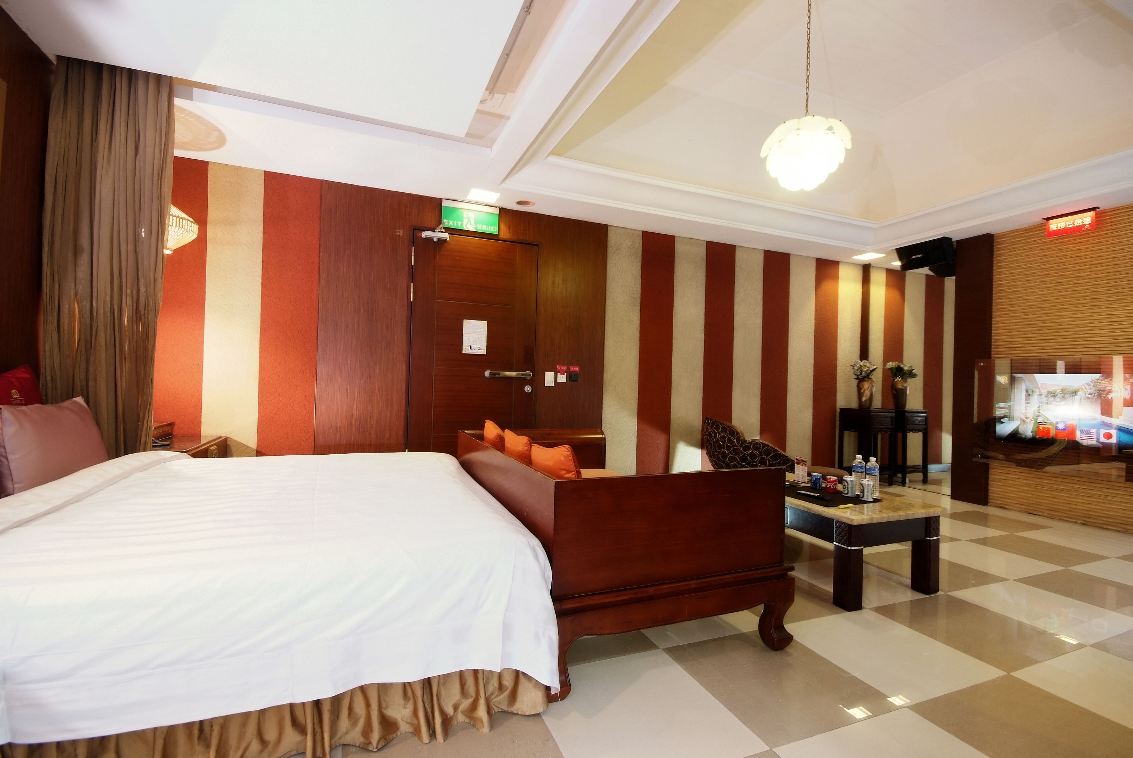 Quarto de hotel com cama, sofá, mesa e balcão de recepção.