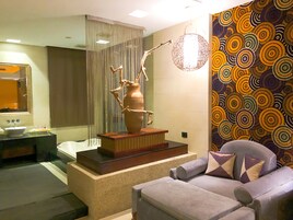 A modern bathroom with a bathtub, a sink, a decorative vase, and a patterned wall.