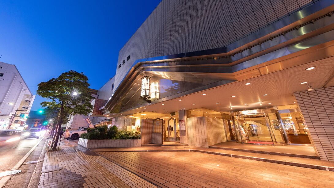 A modern building with a tiled facade, a covered entrance, and a well-lit interior.