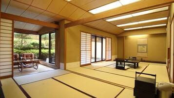 A tatami mat room with sliding doors, a tatami mat table, a low table, and a traditional Japanese-style room with a view of greenery outside.