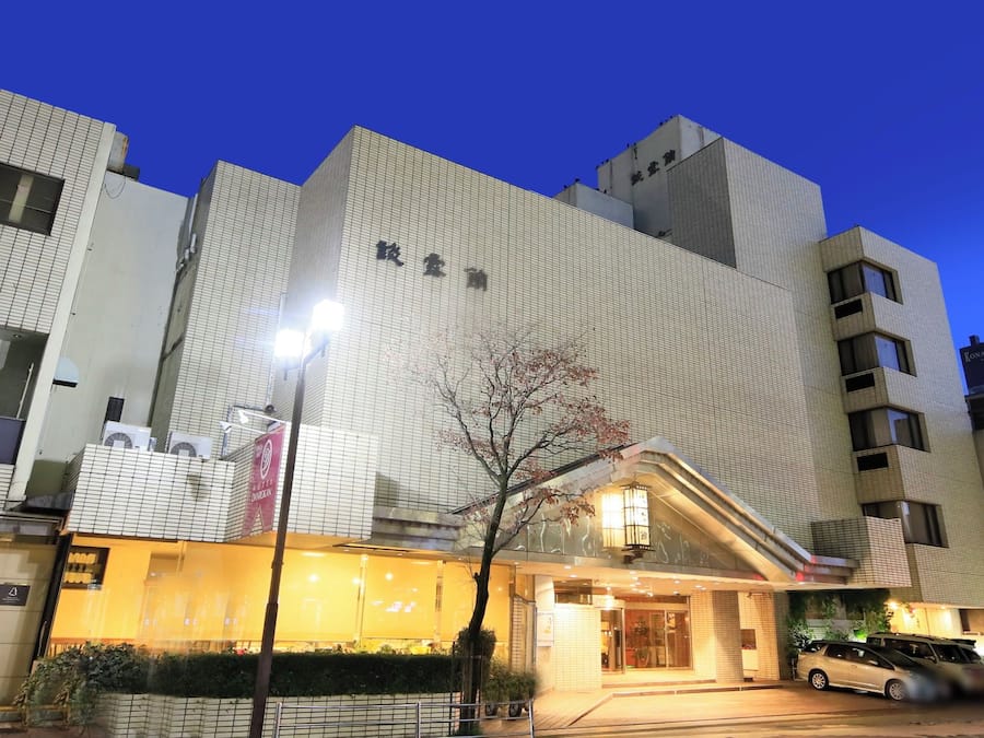 A hotel with a modern facade, a visible entrance, and a parking area.
