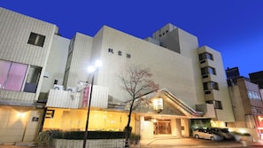 A hotel with a modern facade, a visible entrance, and a parking area.