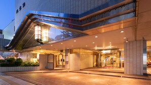 A modern hotel entrance with a glass facade, a covered walkway, and a well-lit lobby area. - Hotel Danrokan (Kofu)