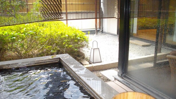 A small outdoor water feature with a wooden bucket nearby. - Hotel Danrokan (Kofu)