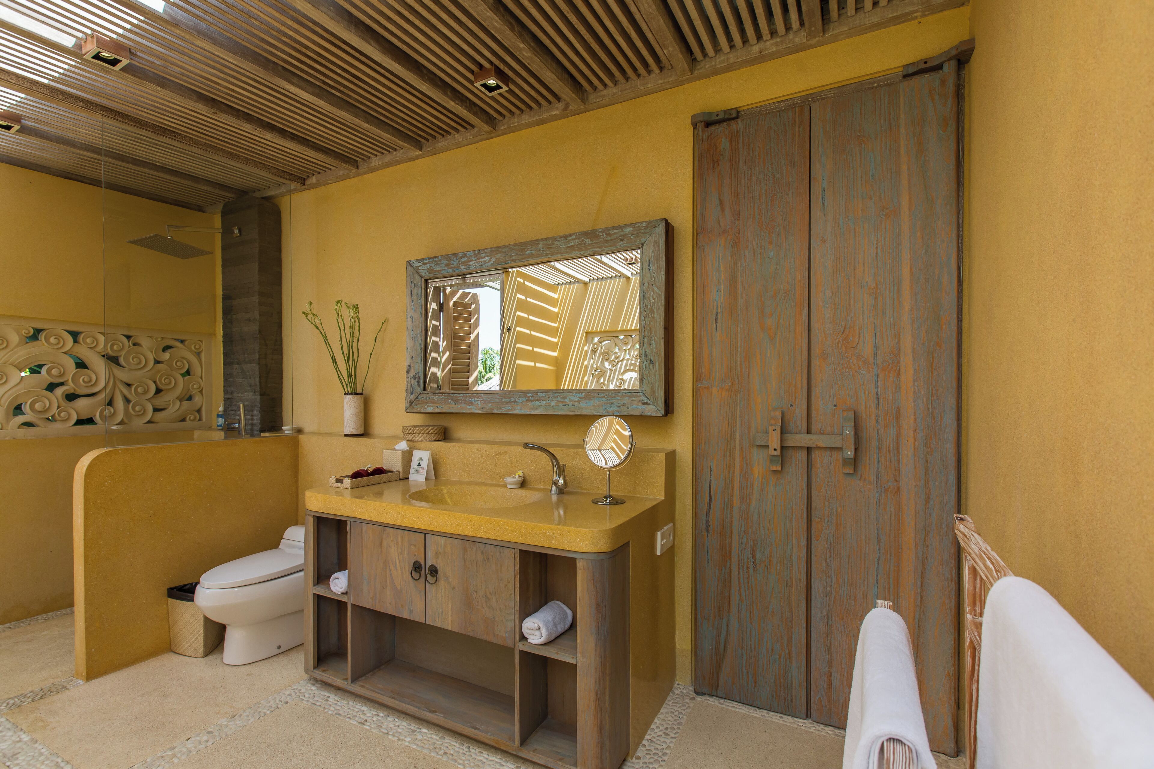 A bathroom with a wooden vanity, a sink, a toilet, and a mirror.