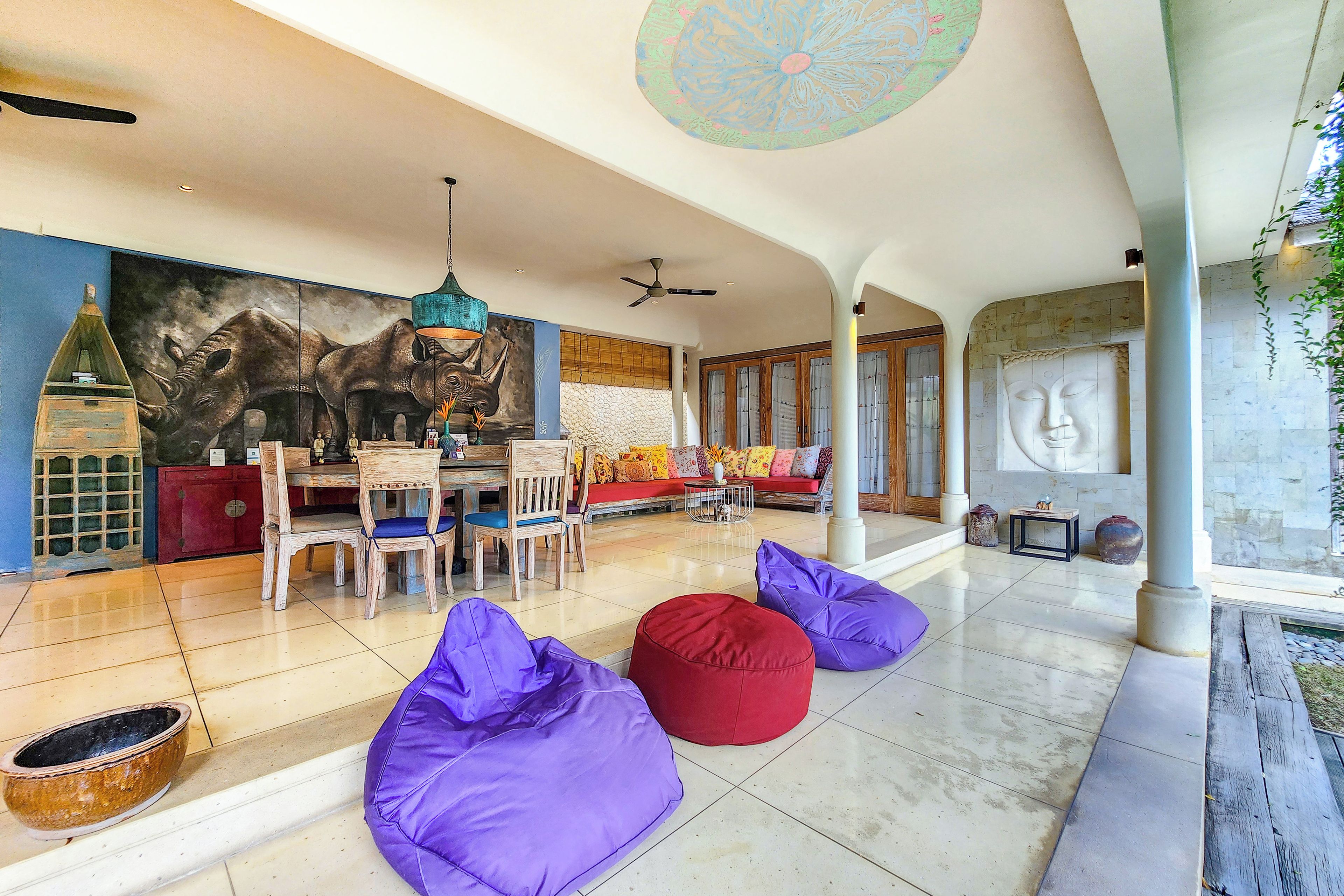 A spacious living area with a large mural, a dining set, and seating arrangements.
