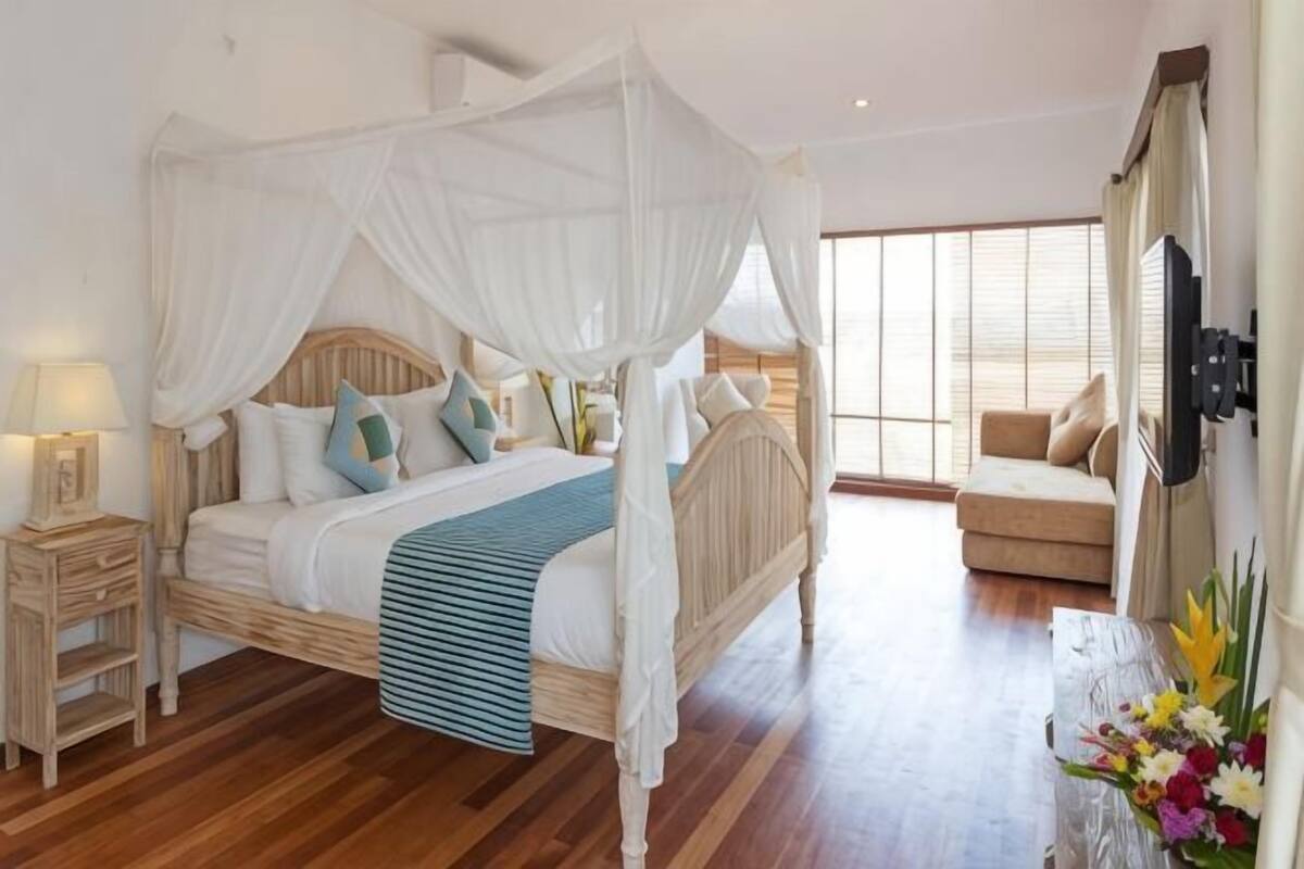 Une chambre à coucher avec un lit à baldaquin, une table de chevet, une commode, un canapé et une grande fenêtre.