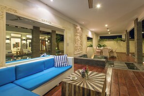 Ein modernes Interieur mit einem blauen Sofa, einem runden Couchtisch und einer Essecke mit Stühlen und Tisch.