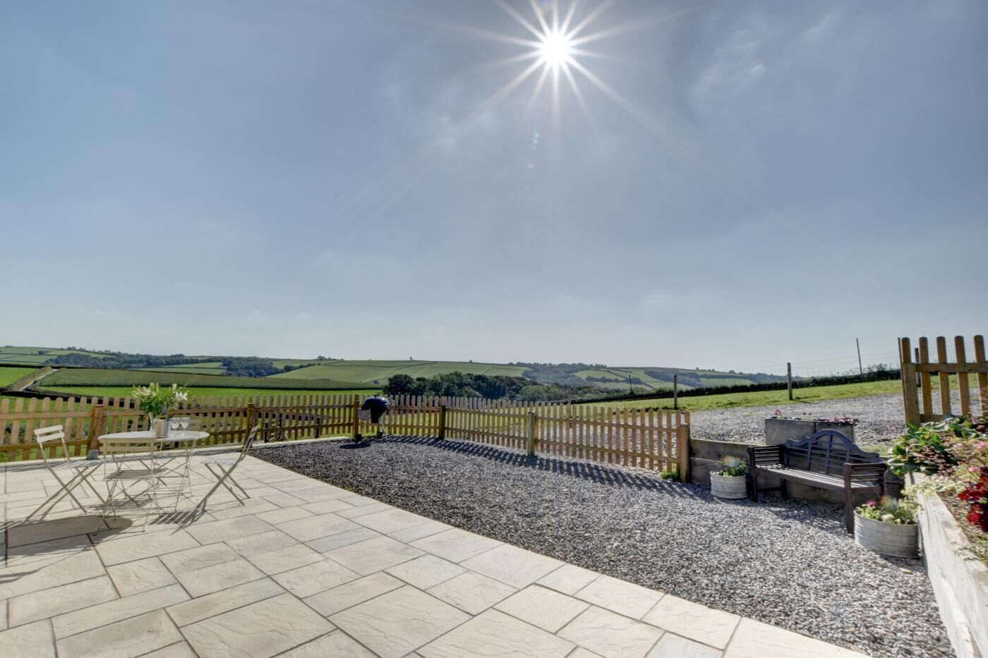 Un patio con vistas a colinas onduladas, una valla de madera y mobiliario de exterior.