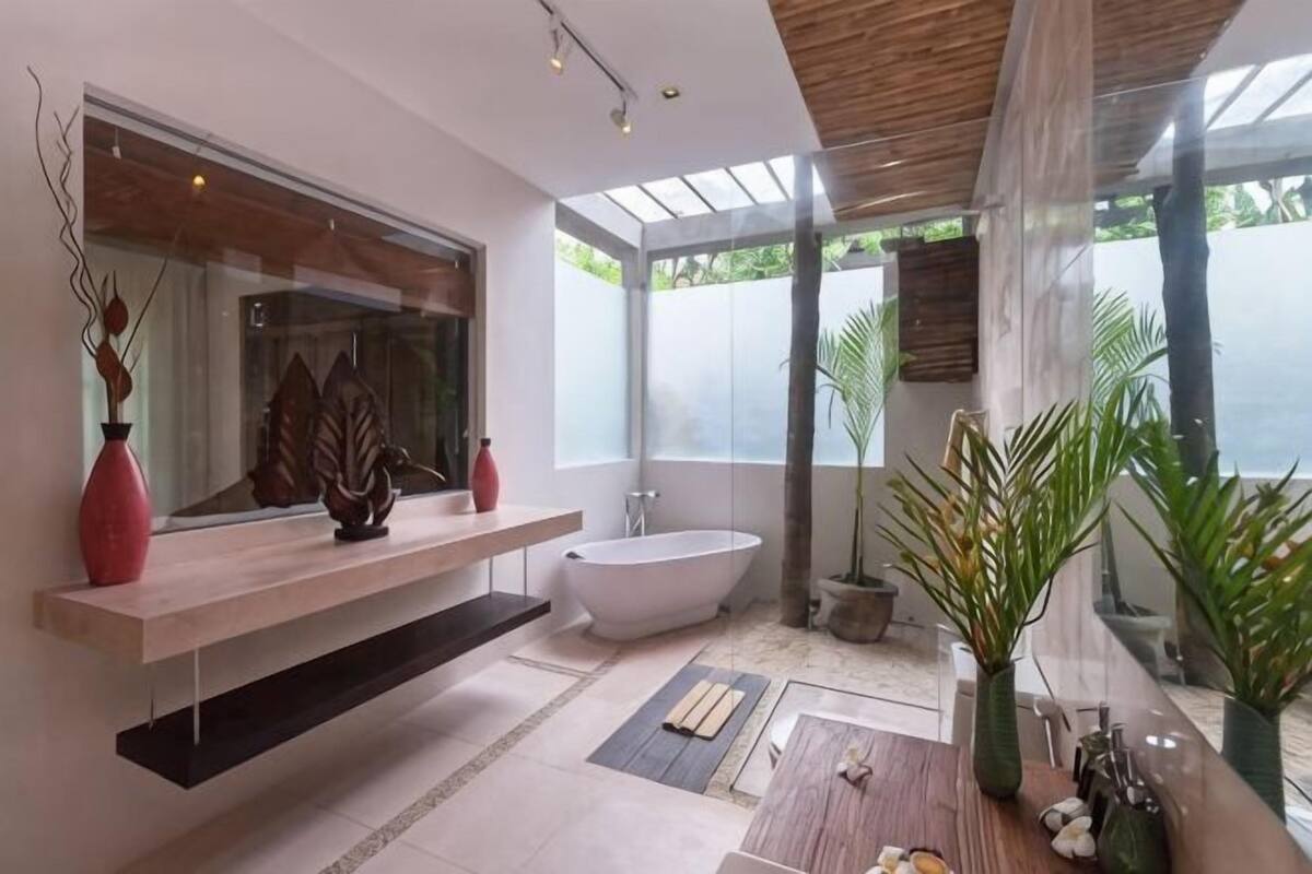 A modern bathroom with a freestanding bathtub, a large mirror, and a wooden vanity.