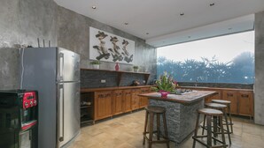 A modern kitchen with a central island, bar stools, a refrigerator, and a water dispenser.