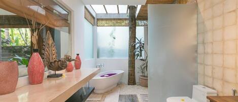 Un baño moderno con una bañera independiente, un inodoro y un tocador decorado.