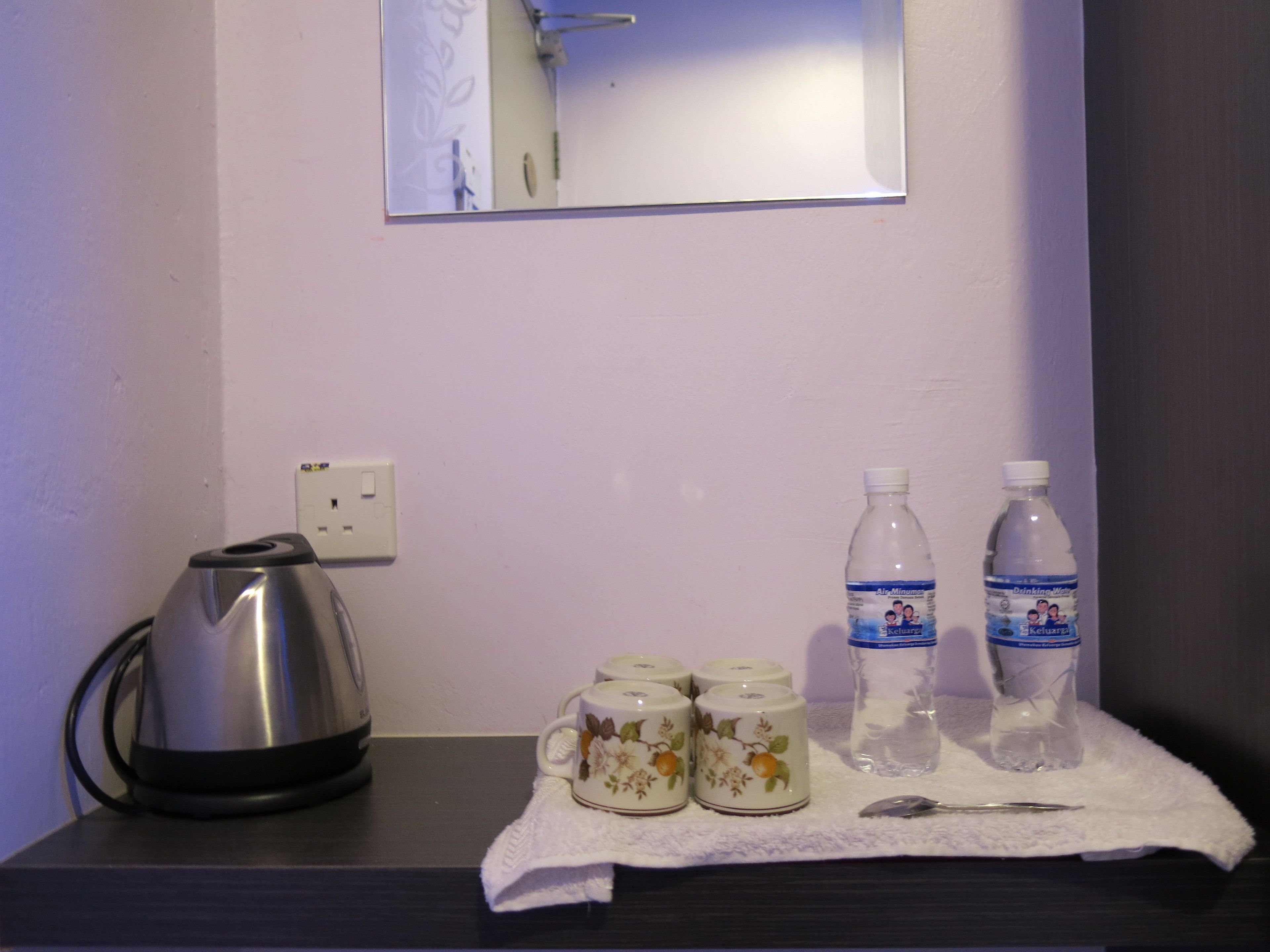 A kitchen counter with a kettle, two water bottles, and three decorative cups.