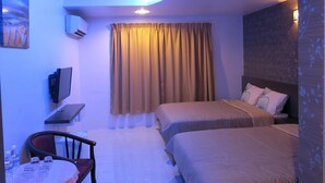 Una habitación de hotel con dos camas, televisor, escritorio y silla.